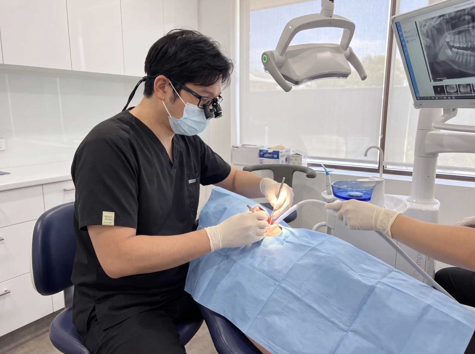 Dr TK Kim performing a procedure with the patient fully draped at Mirabel Dental Hornsby